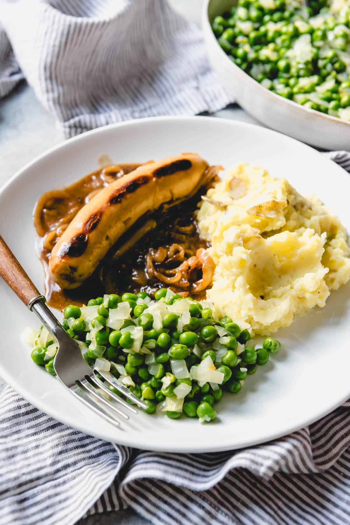An image of peas with bangers and mash.