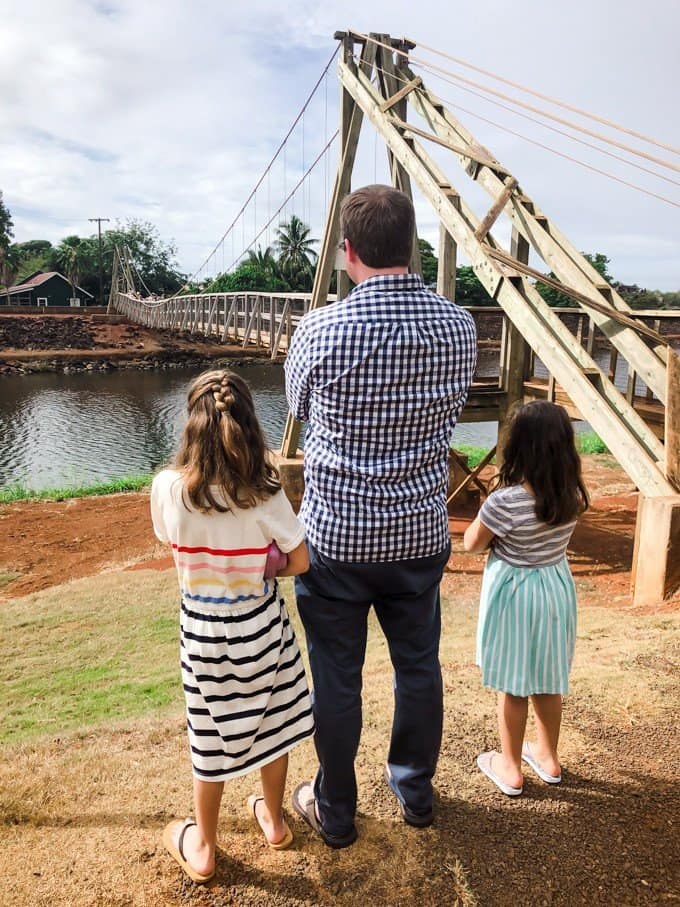 a man and 2 daughters looking at a river under the bridge