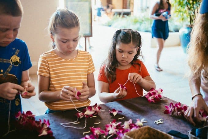 kids standing at a table making flower leis