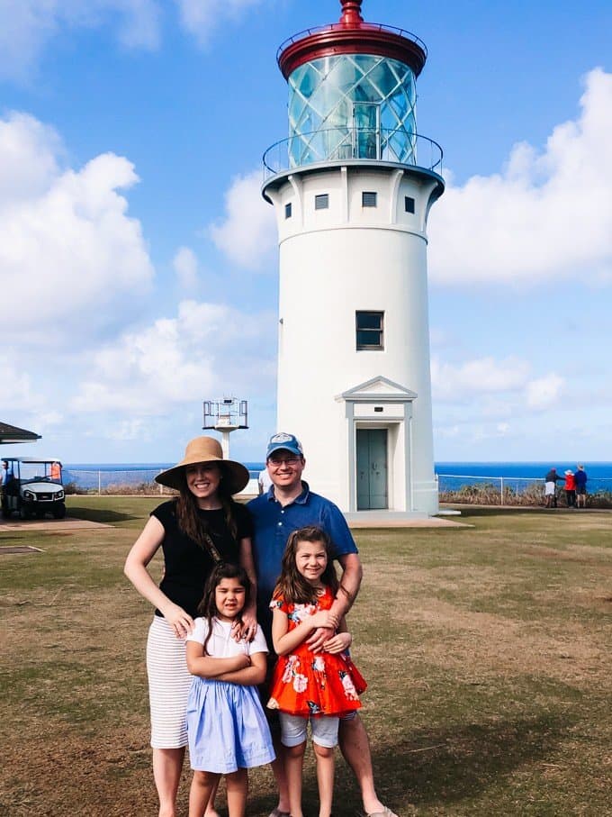 a family of 4 posing for a photo in front of a lighthouse