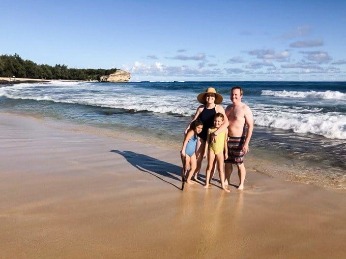 a family of 4 standing near the water at the beach