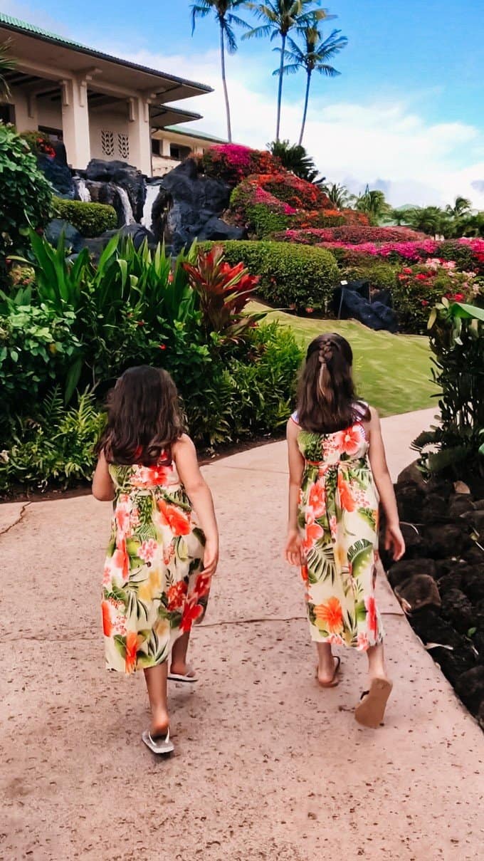 two girls in matching floral dresses walking on the sidewalk
