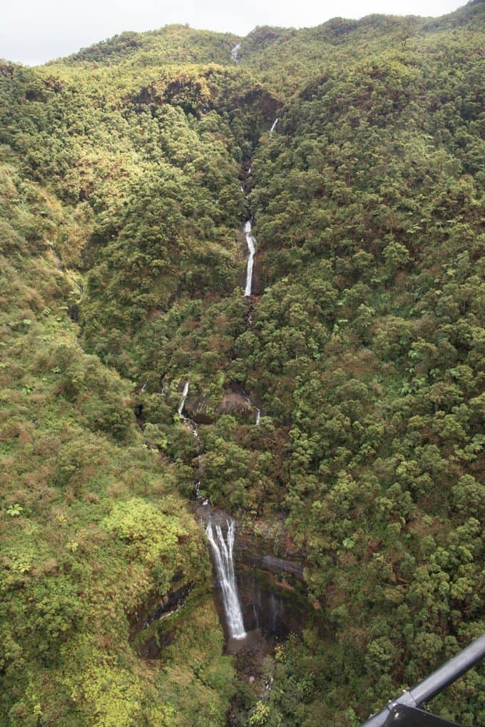 a waterfall through the green hills