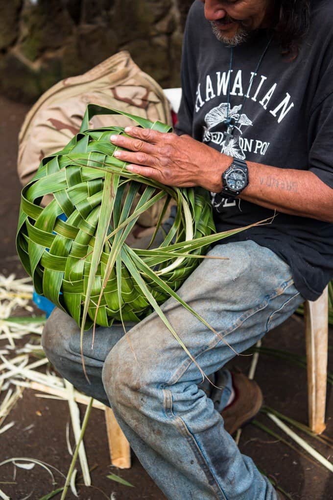 a green leaf woven basket being handmade by a man