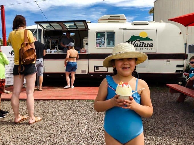 a girl in a blue bathingsuit holding a shave ice