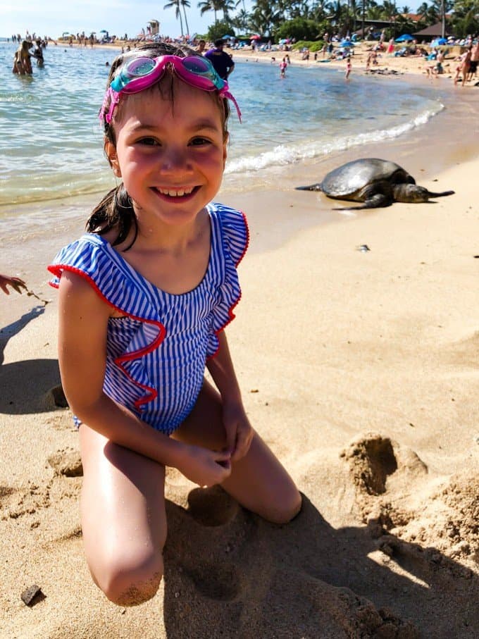 a girl on a sandy beach with a turtle in the background