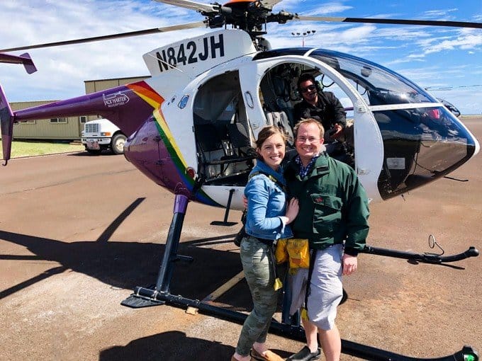 a couple posing for a photo in front of a helicopter