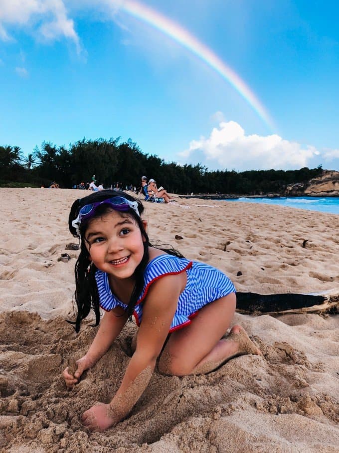 a girl playing in the sand at the beach