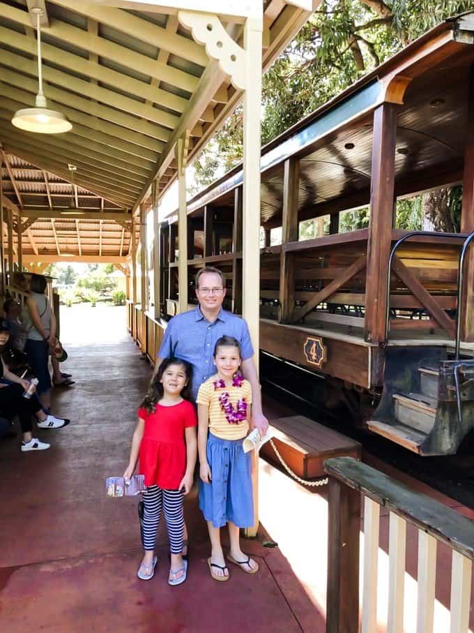 a man and two girls standing near a train