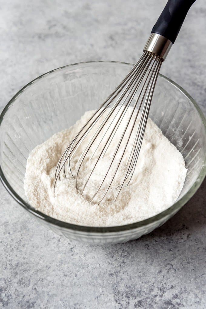 An image of flour, sugar, and salt being whisked together in a bowl.