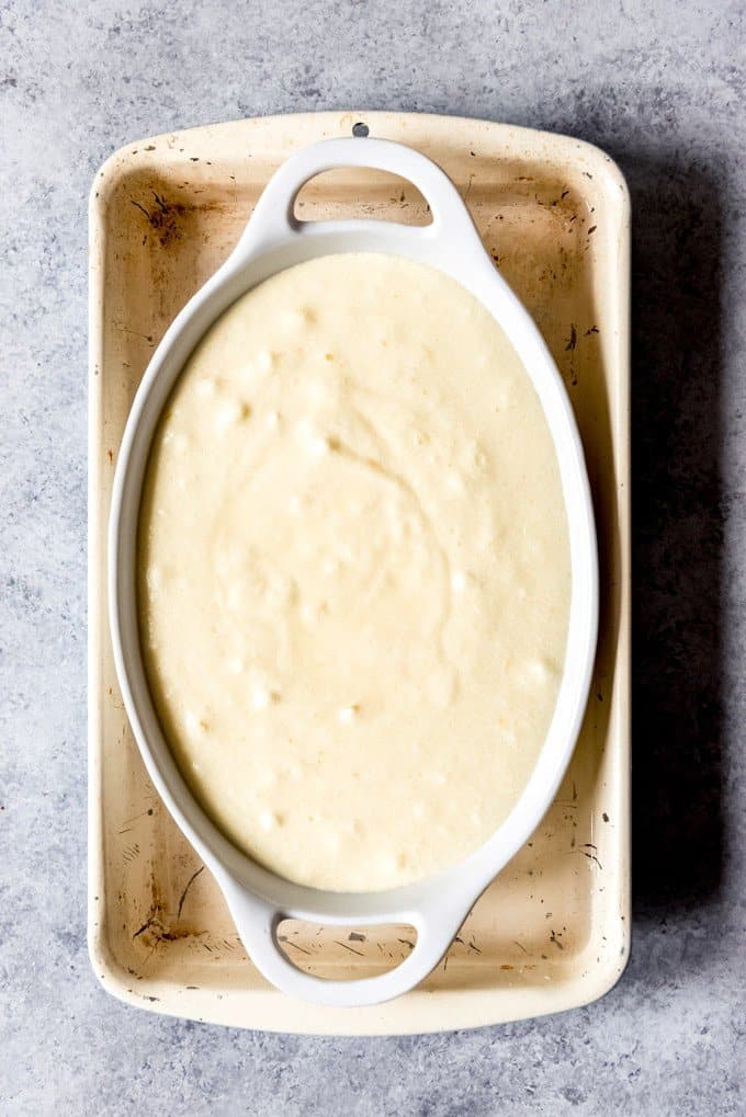 An image of a Meyer lemon pudding cake in a pan set inside a larger pan filled with water for a water bath.