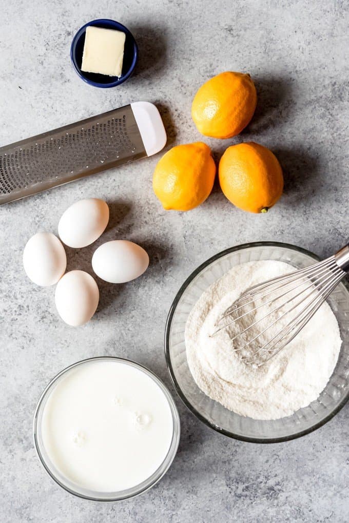 An image of butter, Meyer lemons, eggs, flour, sugar, and milk for baking a lemon cake.