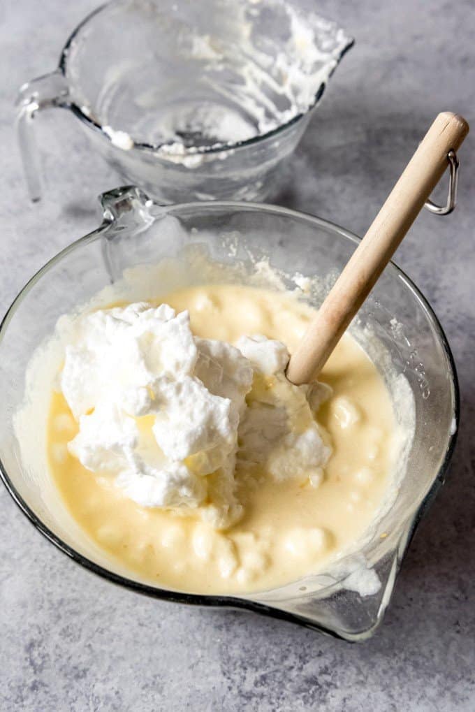 An image of stiff egg whites being folded into a meyer lemon pudding cake batter.