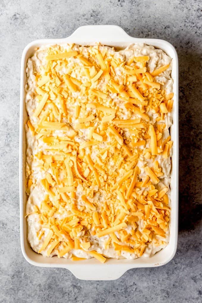 An image of au gratin potatoes with shredded cheese sprinkled over the top and ready to be baked in the oven.
