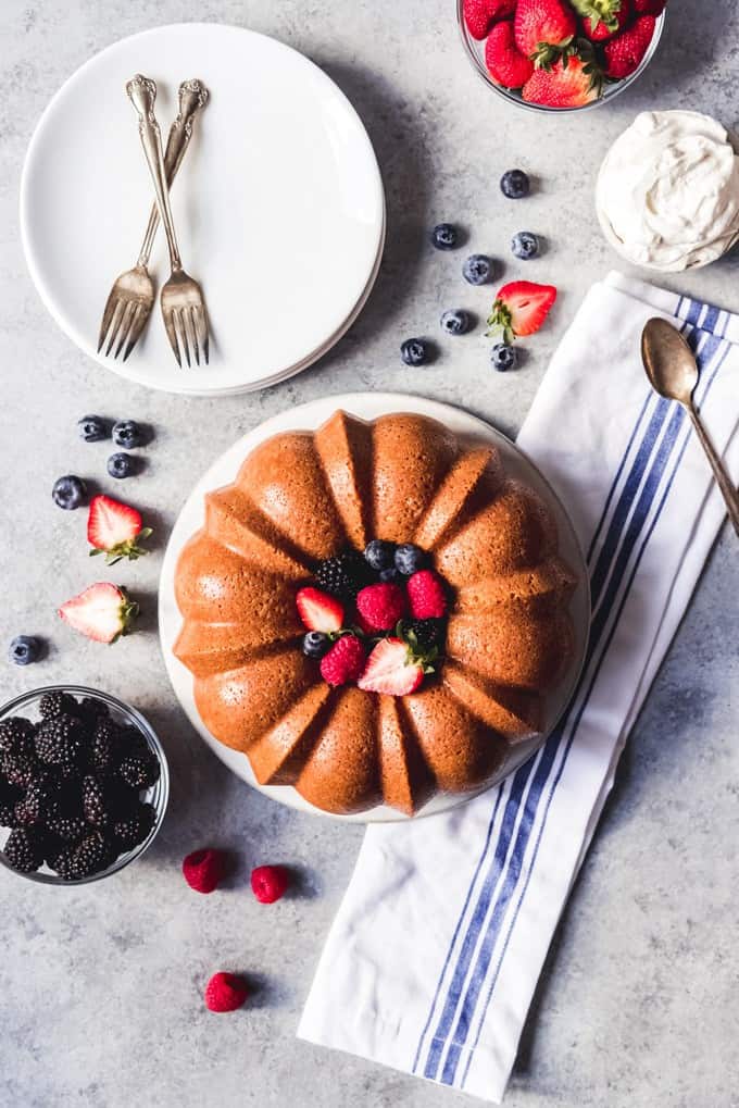 An image of a pound cake made in a bundt cake pan with fresh berries and whipped cream.