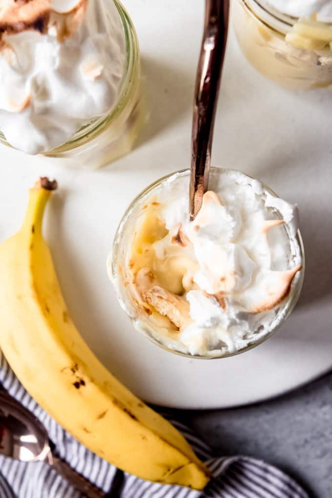 An image of a banana next to a serving of homemade banana pudding with a spoon in it.