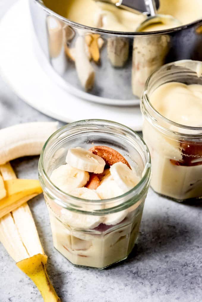 An image of sliced bananas and vanilla wafers in a glass jar with homemade vanilla pudding.