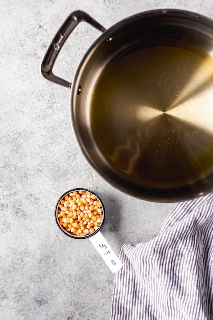 An image of a large heavy bottom pot with oil and a ½ cup of popcorn kernels for making stovetop popcorn.