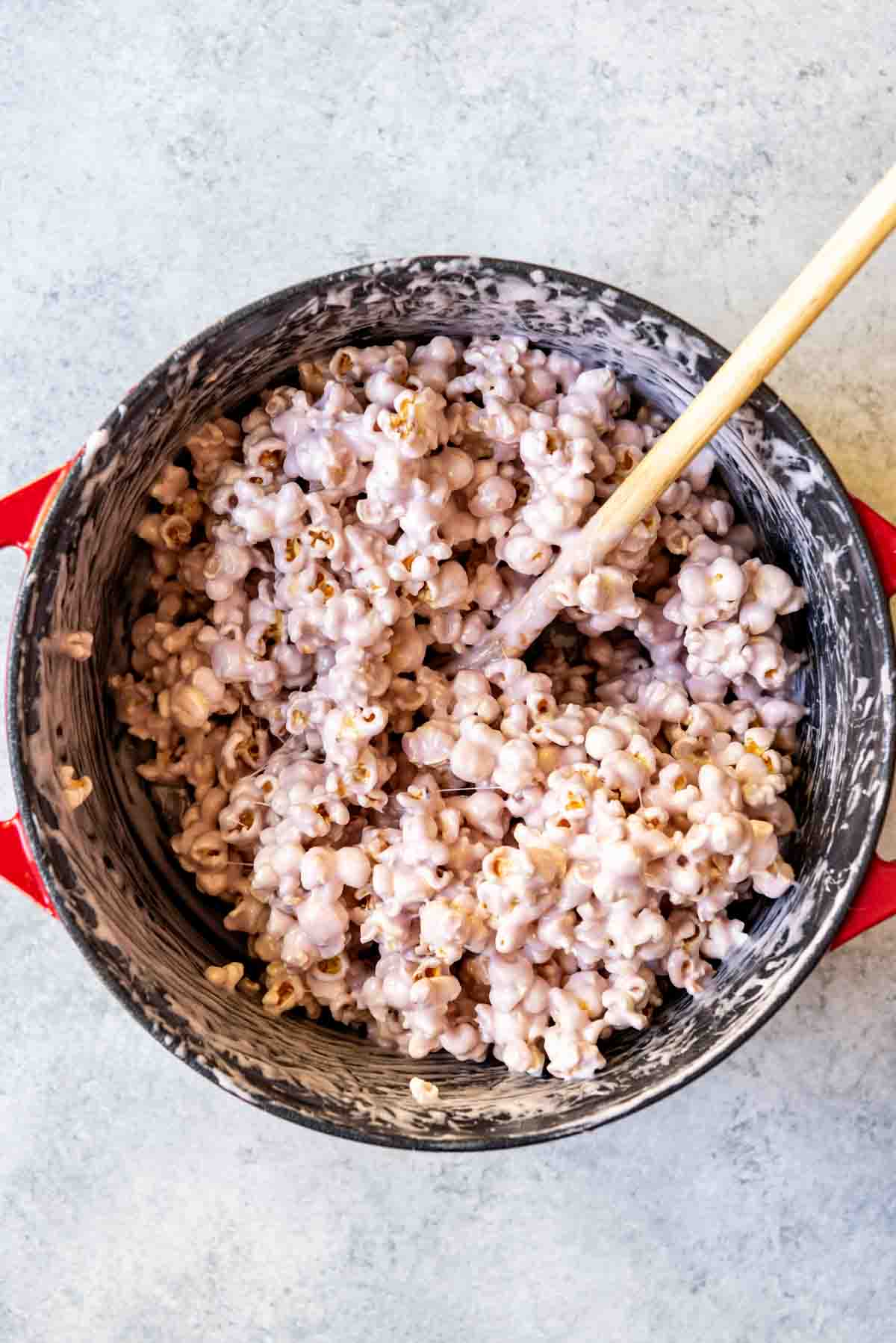 An image of a pan full of popcorn coated in melted marshmallows and butter for easy marshmallow popcorn balls.