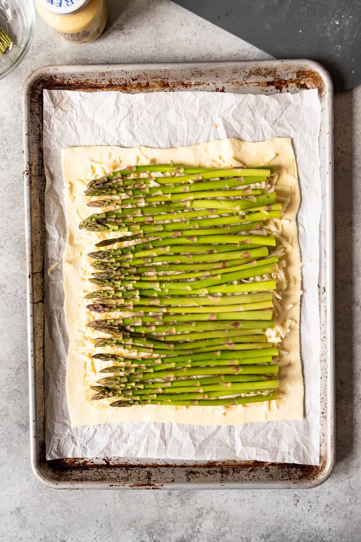 An overhead image of asparagus stalks on top of puff pastry.
