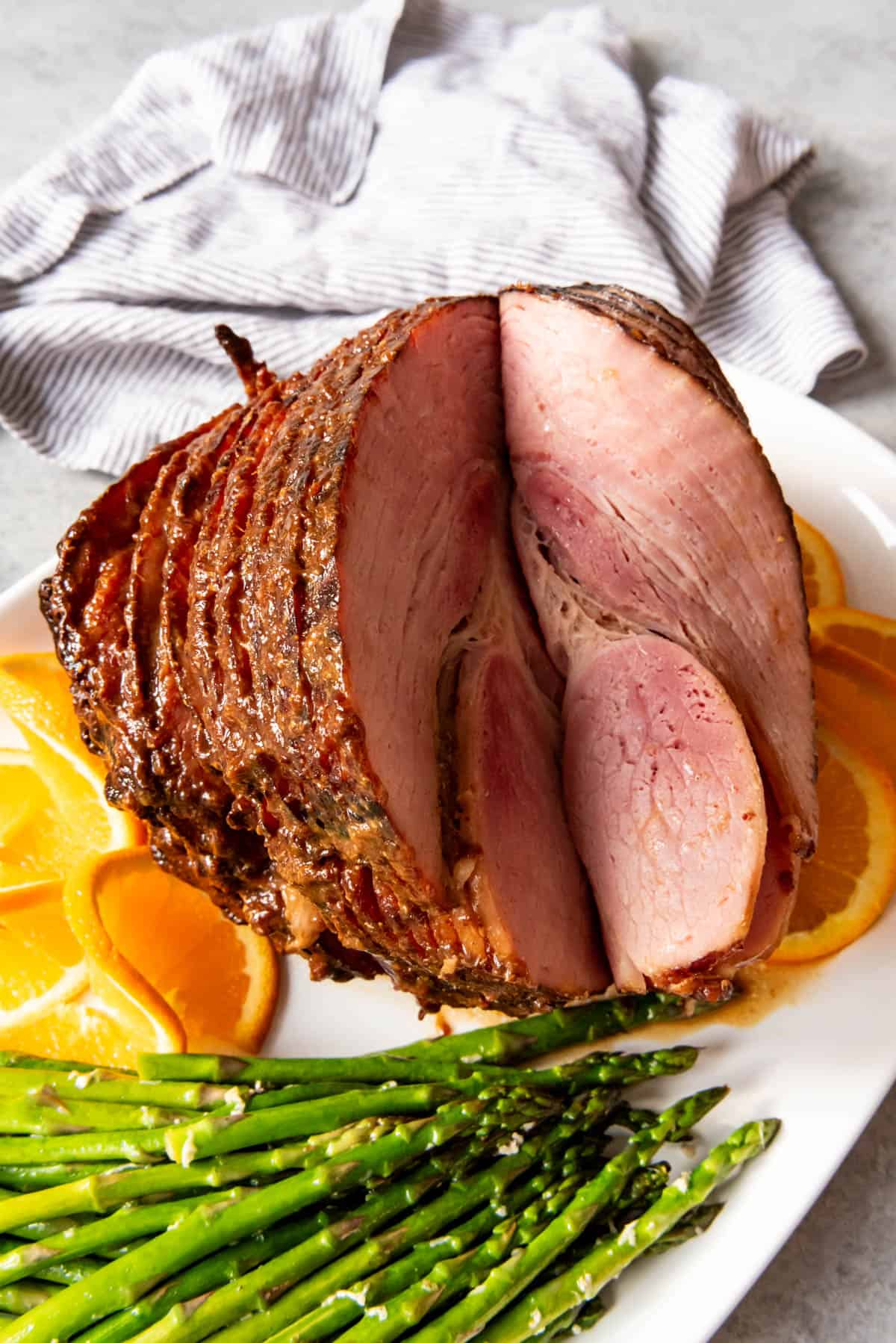 A large Easter ham on a platter with asparagus.