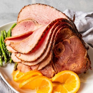 Slices of cooked ham folded over to show the inside of the rest of the ham.