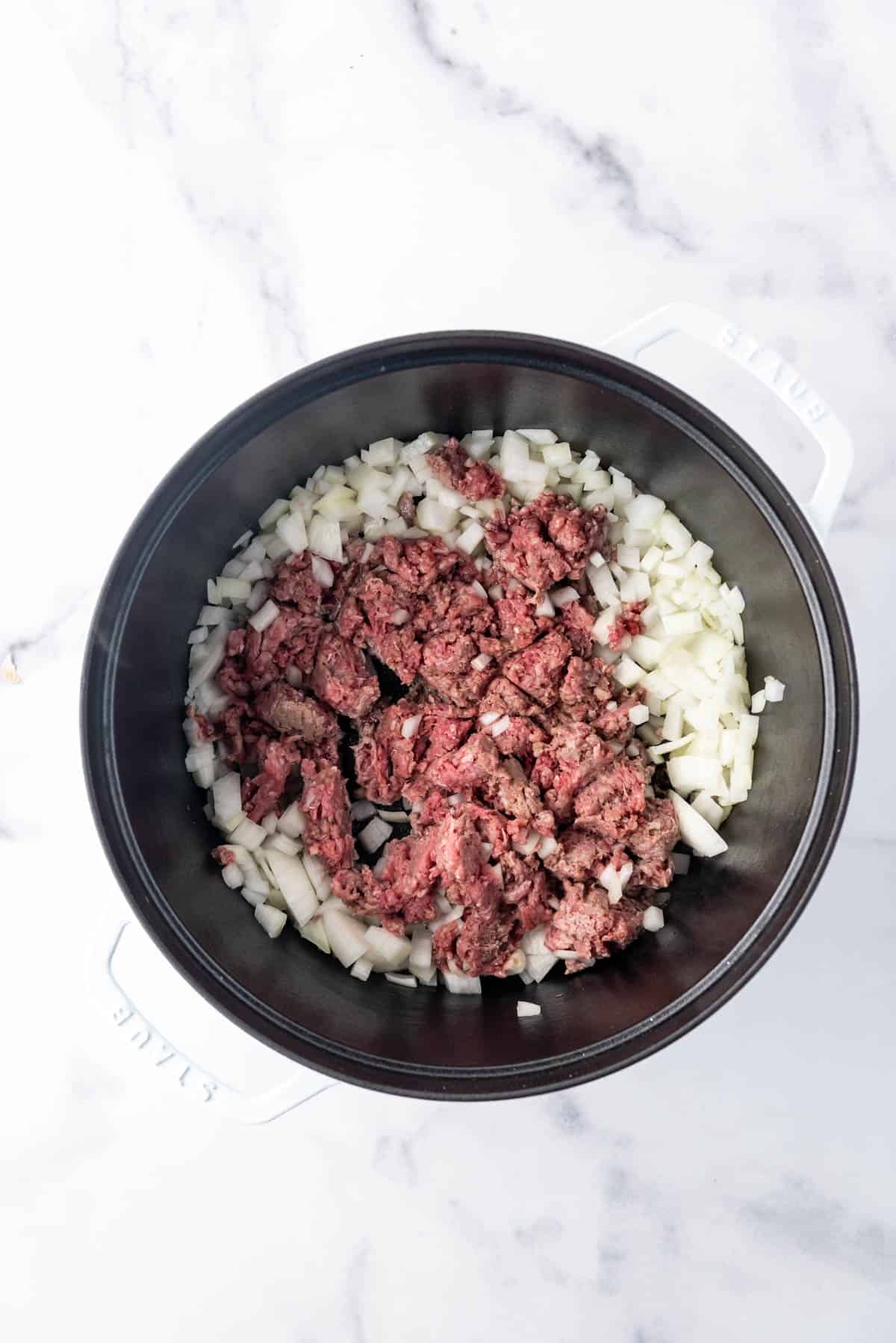 Ground beef and chopped onions in a large dutch oven.