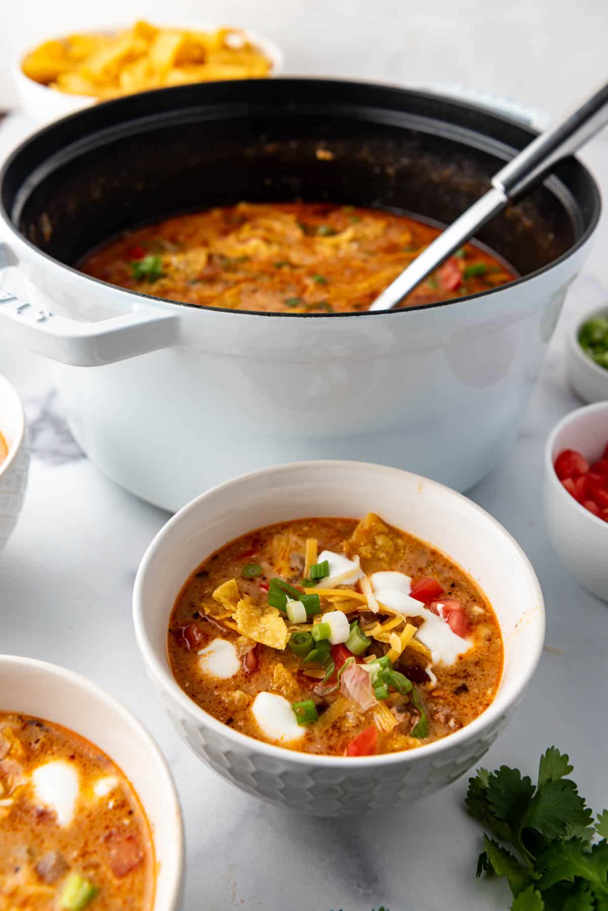 A bowl of taco soup in front of the pot of soup.