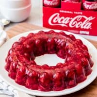 Coca-Cola Jello Salad on a white plate with glass bottles of coke in the background