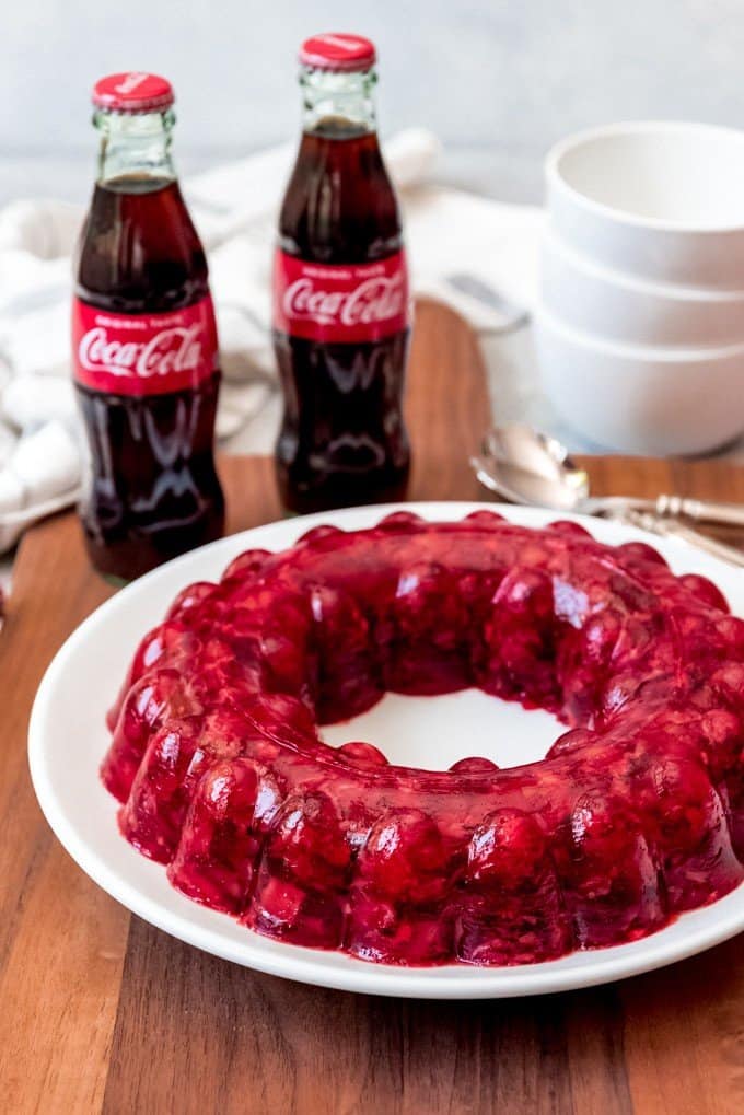An image of two bottles of coca-cola next to a coca-cola jello salad.