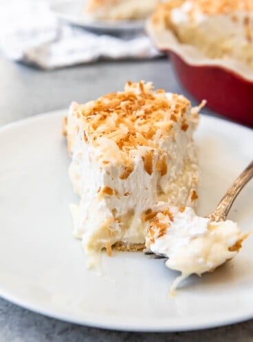 A close image of a slice of coconut cream pie with a bite taken out of it.