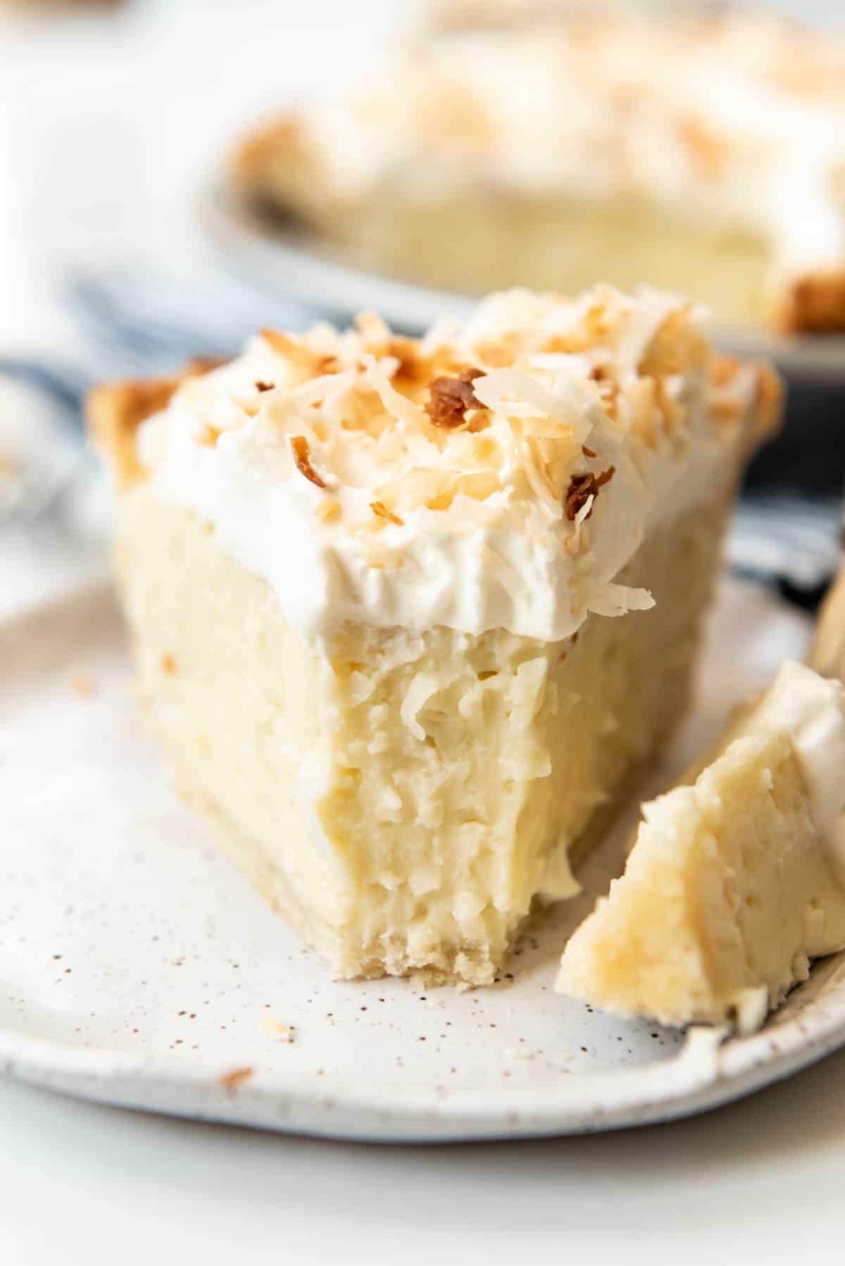 A slice of homemade coconut cream pie with a bite taken out of it.