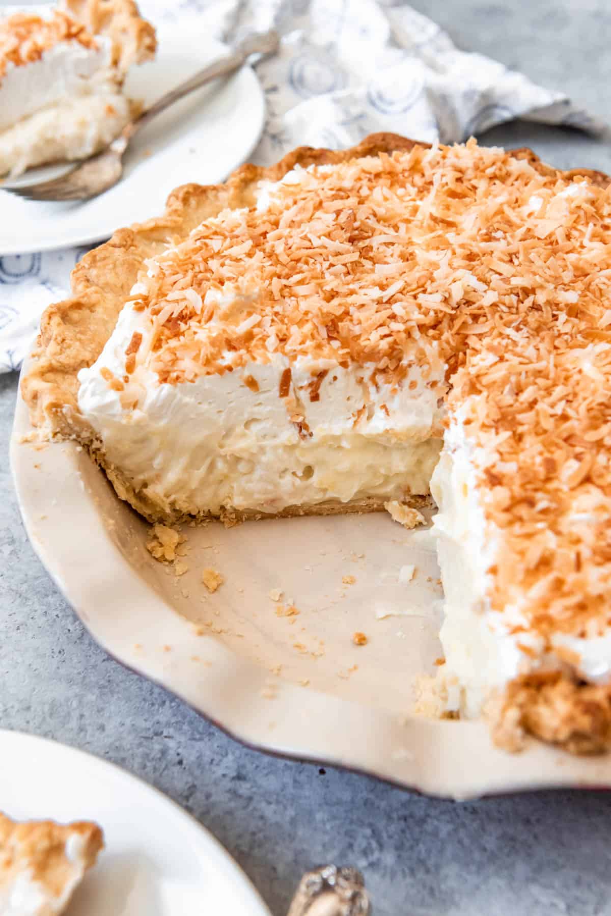 A homemade coconut cream pie with slices removed.