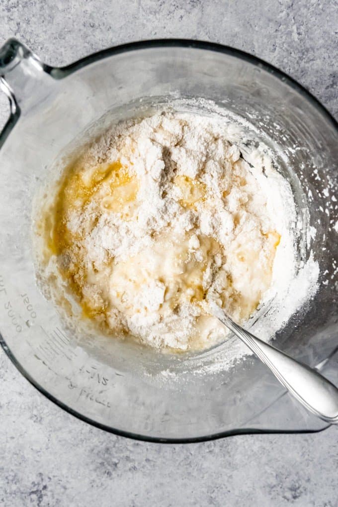 An image of flour, cornmeal, buttermilk, sugar, eggs, and melted butter being mixed up to make a batch of hoe cakes.