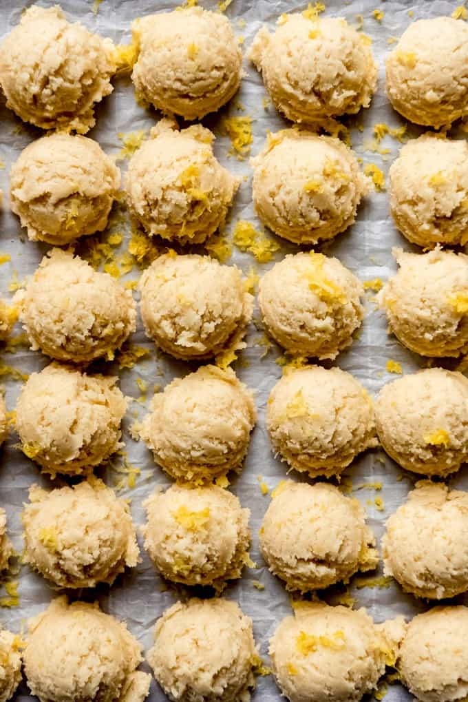 An image of balls of lemon sugar cookie dough on parchment paper.
