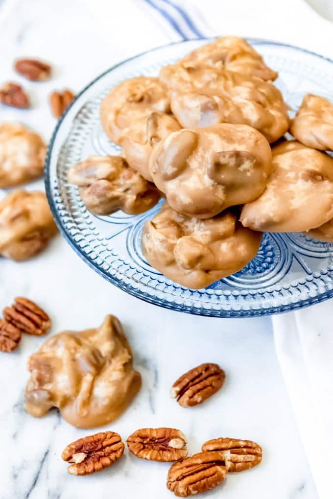 pecan pralines on and off of a blue plate with scattered pecans around it