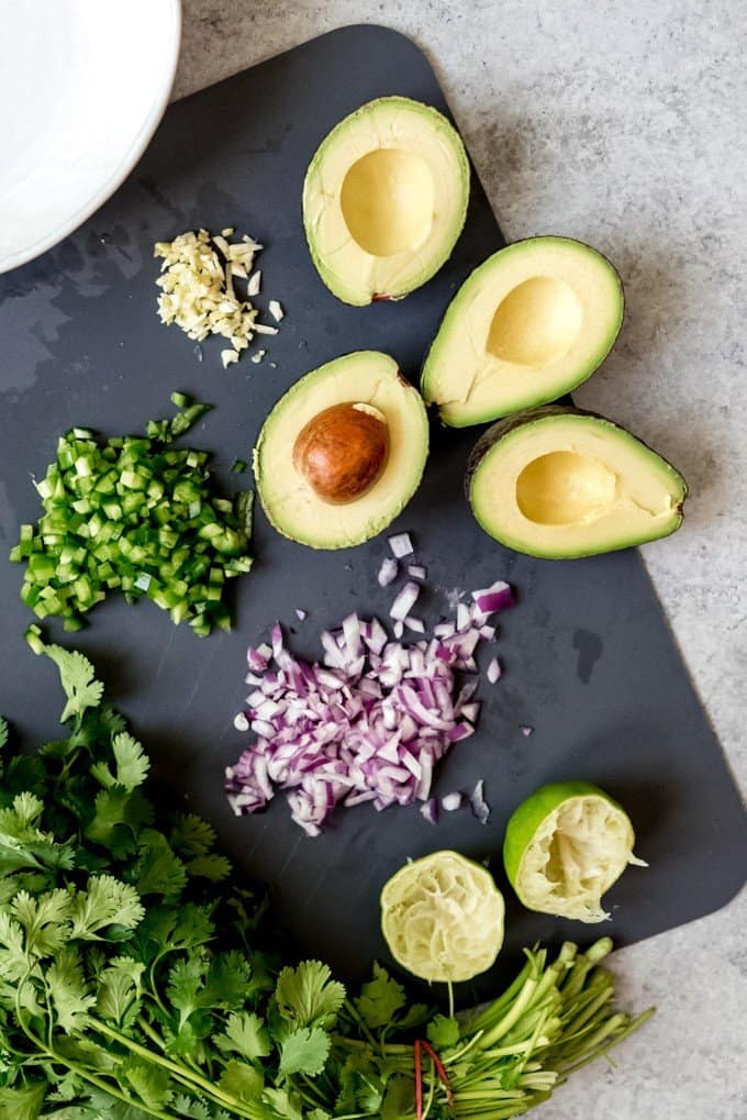 An image of the ingredients for avocado salsa on a cutting board.