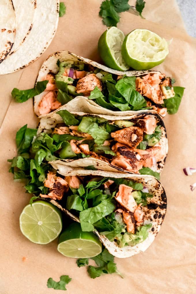 3 salmon tacos arranged side by side with limed halves to the sides