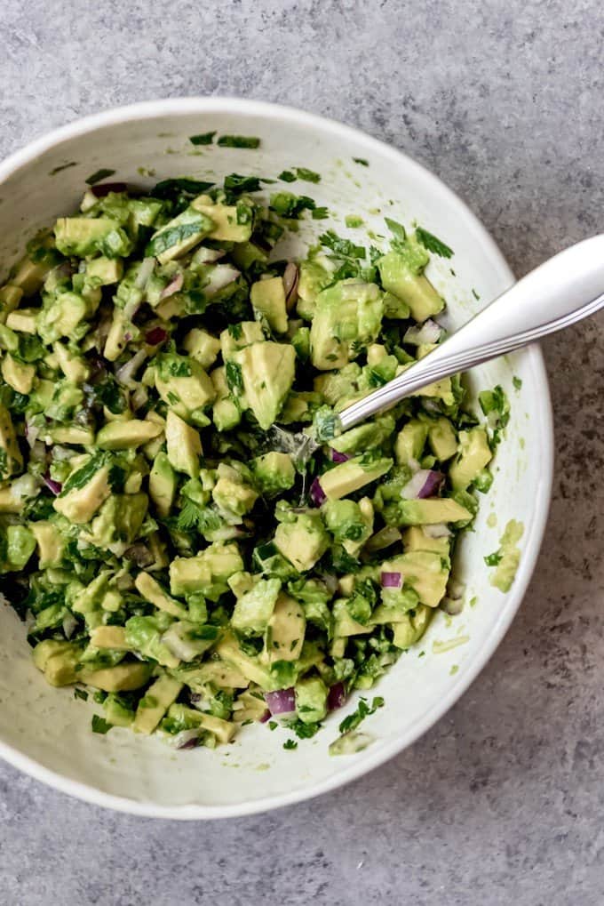 An image of avocado salsa in a bowl with a spoon.