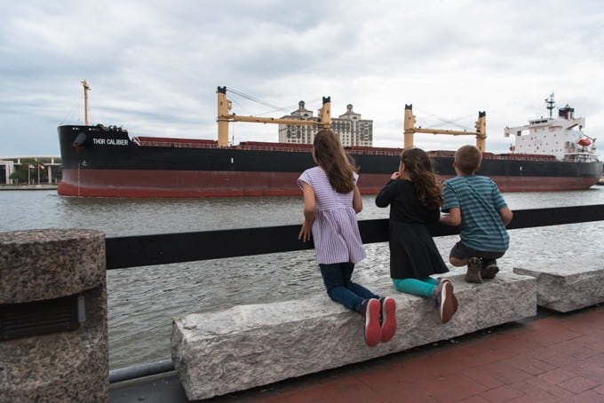 An image of children watching a large container ship on the Savannah River.