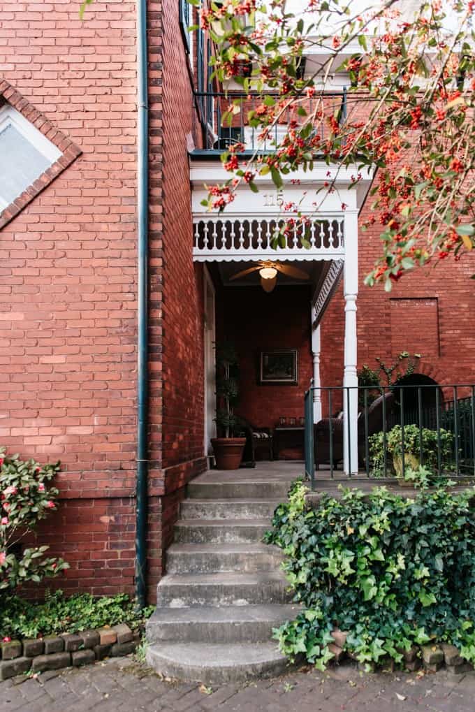 An image of the entrance to a red brick home with white gingerbread trim in Savannah, Georgia.