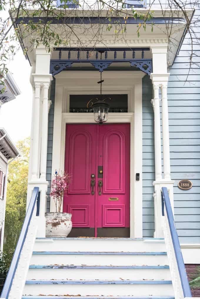 An image of a pink door on a house with blue gingerbread trim.
