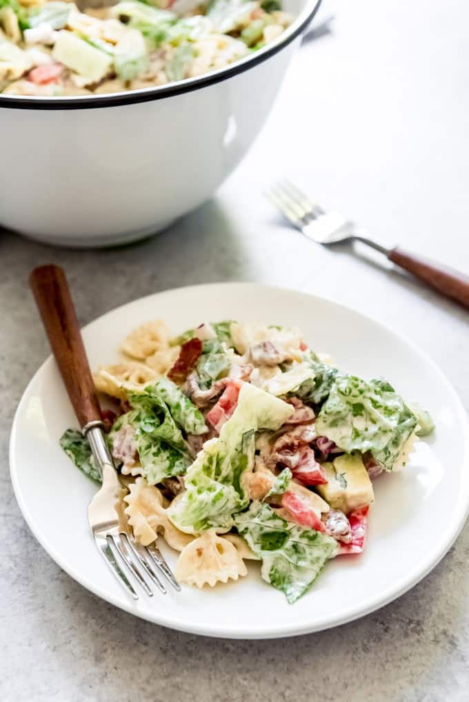 An image of a white plate with a fork and a serving of bacon, lettuce, tomato pasta salad on it.