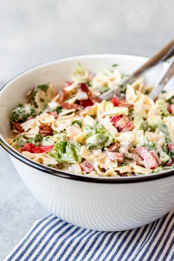 A large bowl of an easy pasta salad with tomatoes, lettuce, bacon, and bowtie pasta.
