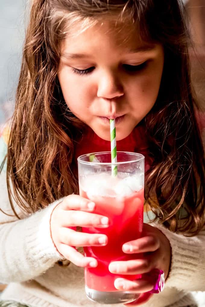 An image of a child sipping a glass of homemade Hawaiian punch.