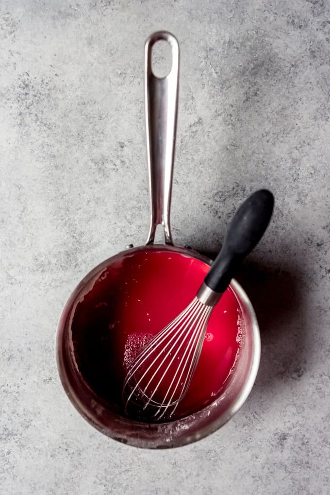 An image of a saucepan with cherry juice, sugar, and cornstarch whisked together to make cherry pie filling.