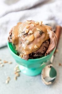 a blue bowl filled with chocolateice cream and topped with peanut butter sauce and chopped nuts