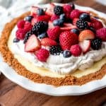 An image of a white chocolate cream pie topped with whipped cream and fresh mixed berries.
