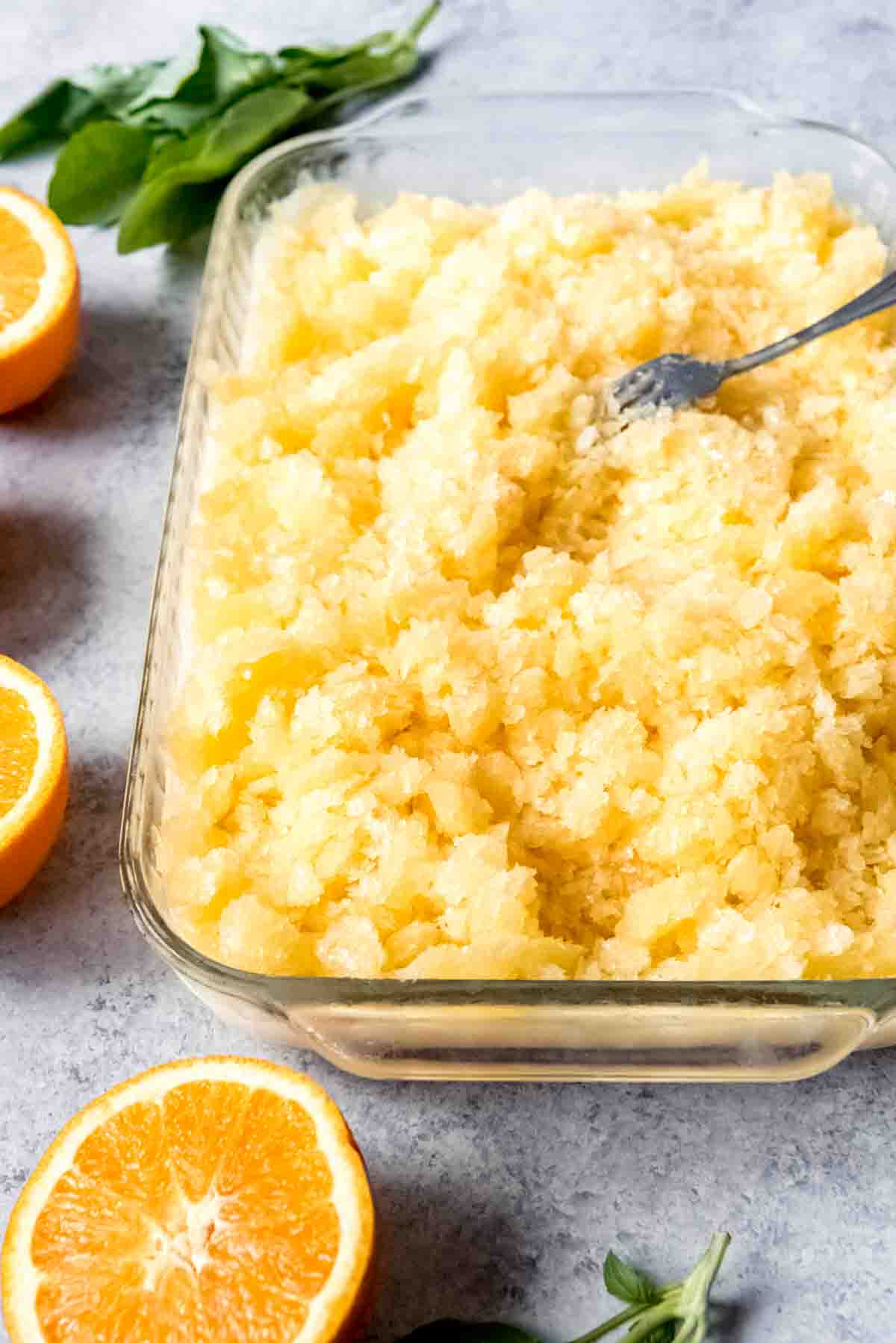 An image of a large dish filled with orange basil coconut granita.