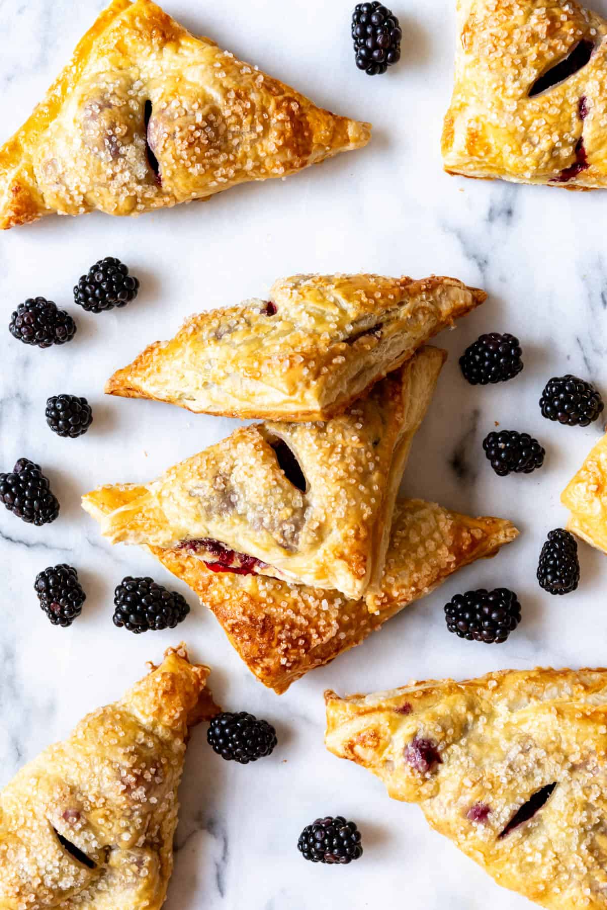 An overhead image of golden brown blackberry turnovers surrounded by fresh blackberries.